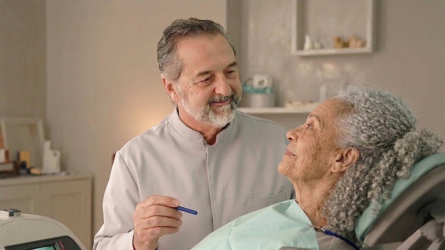 Dr. Hélcio atendendo paciente idosa com carinho